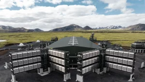Aerial view of Climeworks’ Mammoth direct air capture plant in Iceland, featuring modular carbon removal units against a backdrop of volcanic mountains and green plains.